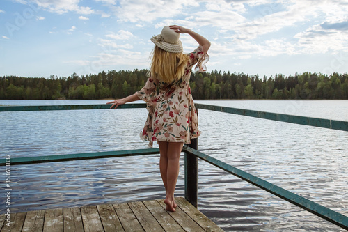 A girl in a beautiful dress on the shore of a forest lake.