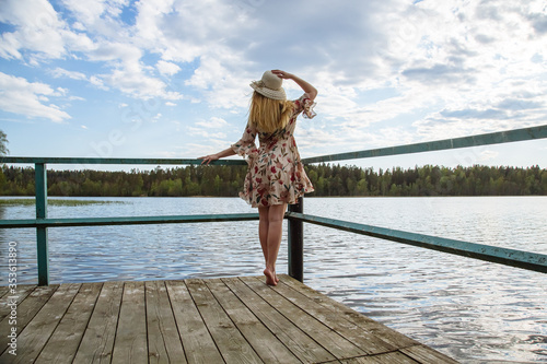 A girl in a beautiful dress on the shore of a forest lake.
