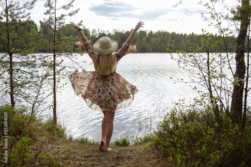 A girl in a beautiful dress on the shore of a forest lake.