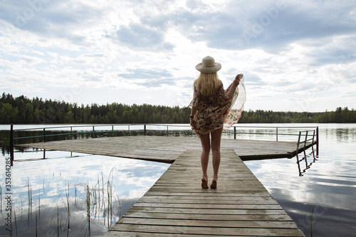 A girl in a beautiful dress on the shore of a forest lake.