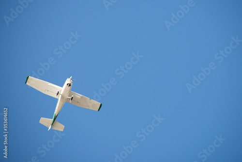 Vom Boden aus: kleines Motor-Flugzeug am wolkenlosen blauen Himmel