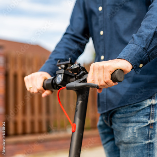 Closeup photo shoot of young man hands on the electro scooter's steering wheel.