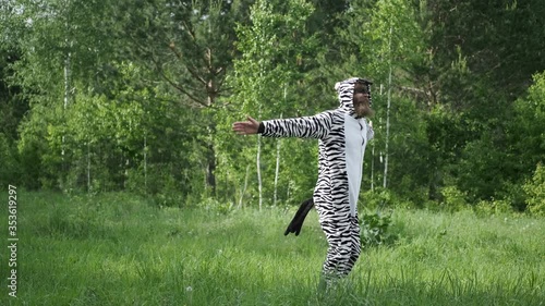 a man in a Zebra costume,with a painted face, bright emotion, jumping in the forest, slow shooting, Sunny weather, funny moment, good mood