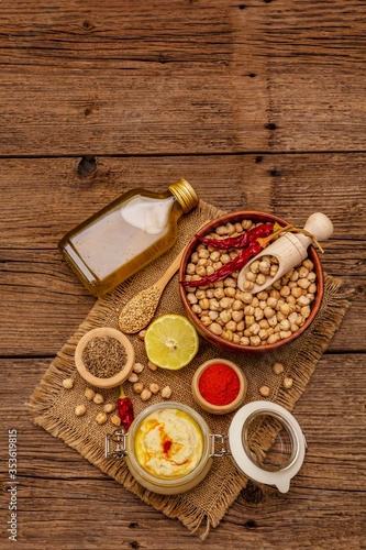 Hummus on old wooden boards background. Dry chickpea, olive oil, lemon, cumin and chili pepper