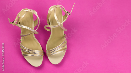 Women's beige sandals with rhinestones on high heels, on a pink background. Women's shoes. The view from the top