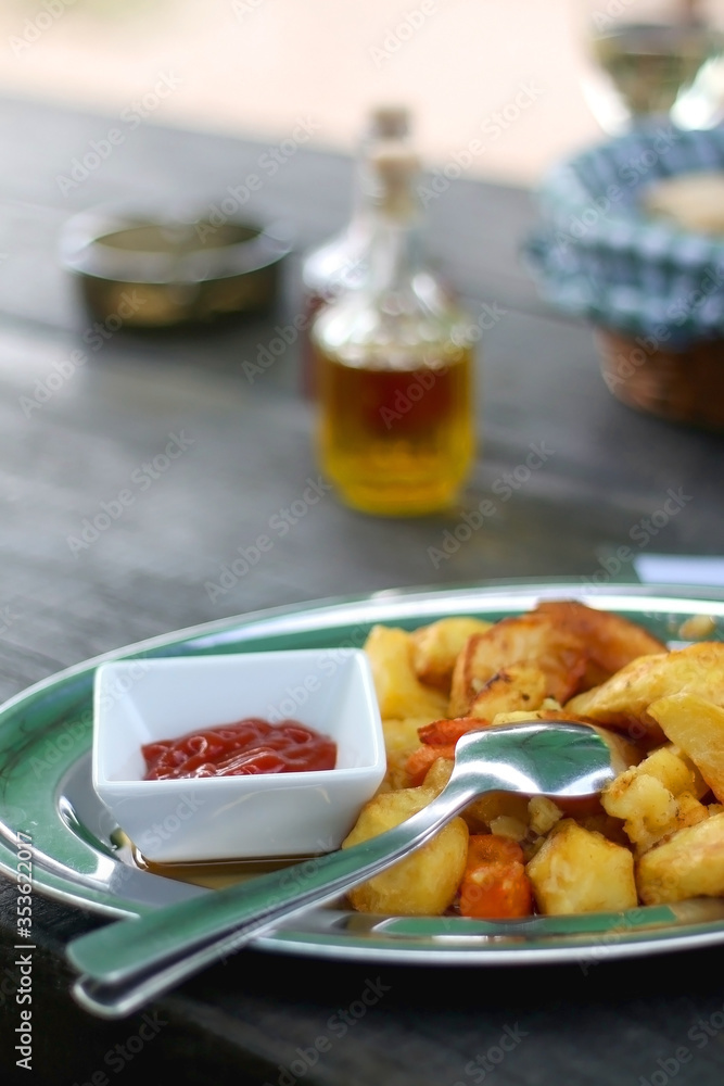 Baked potatoes and carrots with tomato sauce, served on a table. Selective focus.