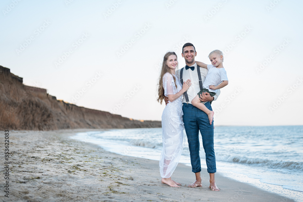 Beautiful young family on a sea background. Dad keeps little son in his hands. Happy family