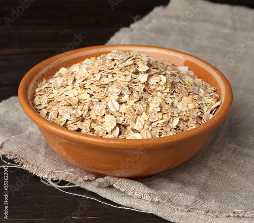 raw oatmeal in a brown ceramic plate on a wooden table