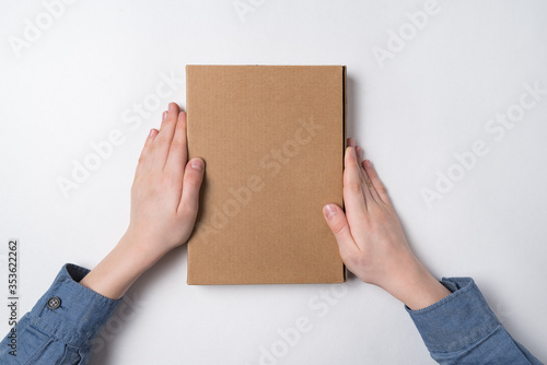 Cardboard box in children's hands on white background. Top view. Copy space. © somemeans