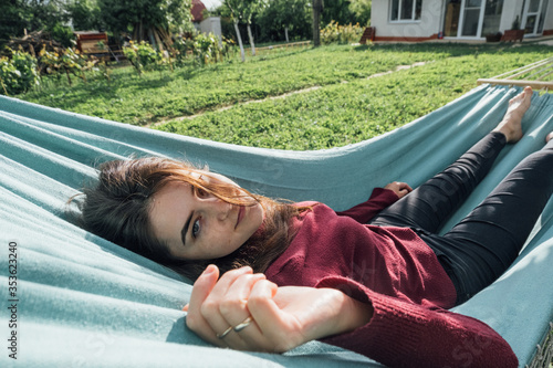The girl is resting on a hammock in the yard