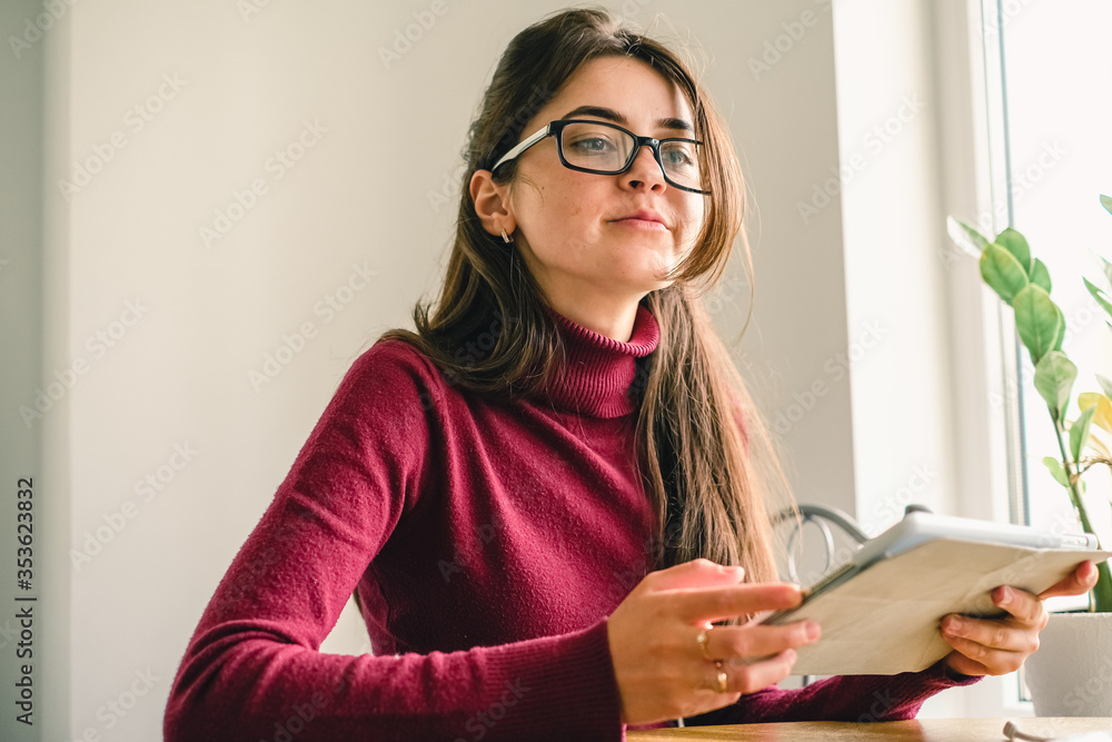 Close up of girl working on tablet from home during period of restrictions. Close up of girl working on tablet from home during period of restrictions.