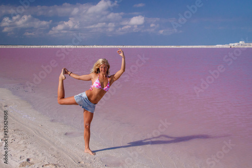 Beatiful girl in bikiny at pink lagoon in Mexico in yoga pose photo