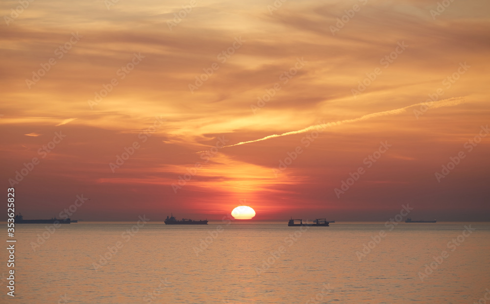 Commercial cargo ships sailing across North Sea in golden sunset light