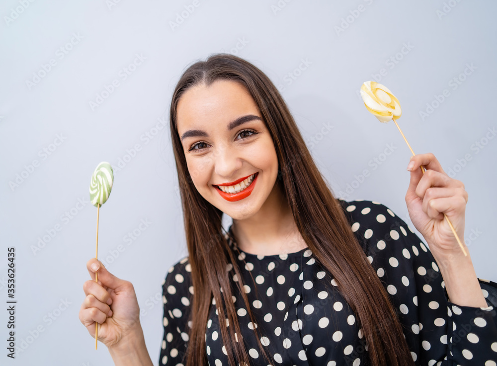 Girl holds two lollipops in hands. Cheerful lady with candies over white background. Girl holds two lollipops in hands. Cheerful lady with candies over white background.