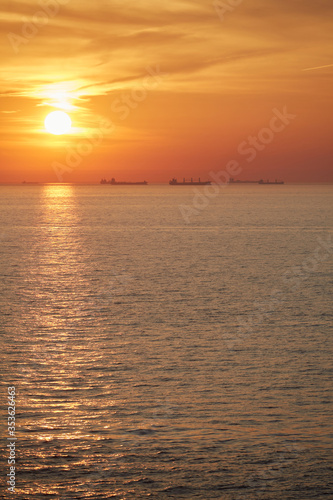 Commercial cargo ships sailing across North Sea in golden sunset light