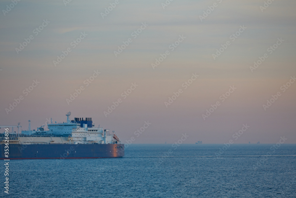 Commercial cargo ship sailing across North Sea in fading dusk light