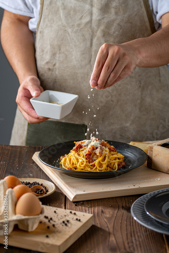 Delicious pasta carbonara on black plate.