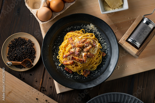 Photos Delicious pasta carbonara on black plate.