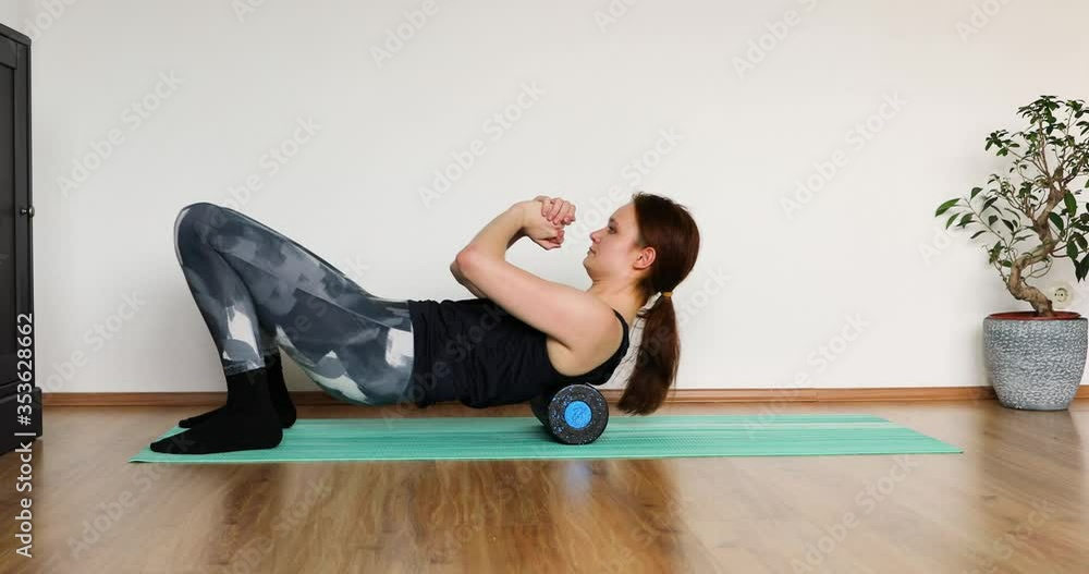 young girl doing her workout at home with black roll for fascia training