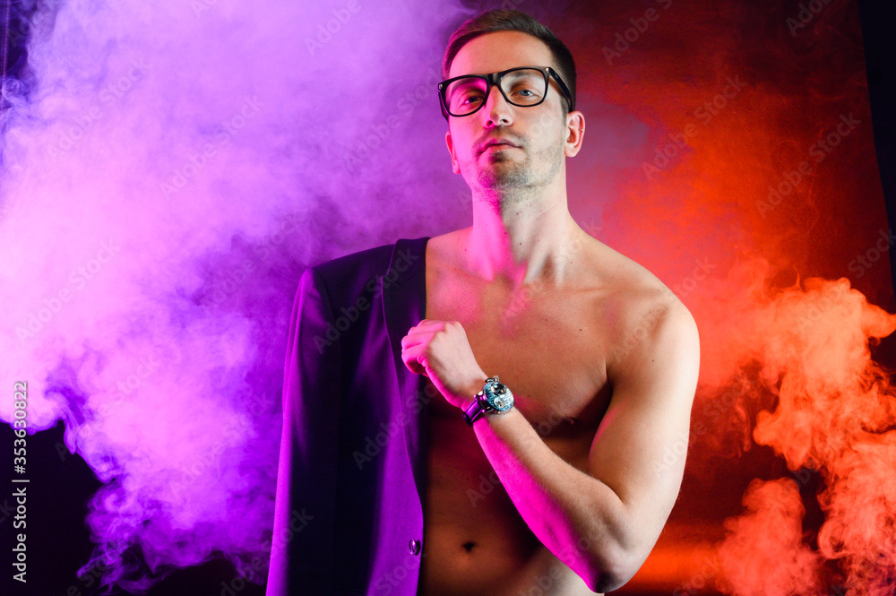 Athletic guy in a jacket shows his body on a bright background with smoke Athletic guy in a jacket shows his body on a bright background with smoke