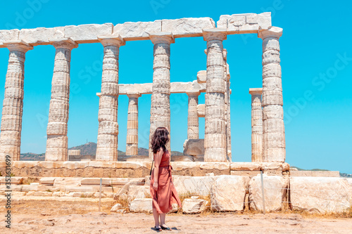A young girl walks around ancient temple of Poseidon on the Cape Sounion during a long-awaited summer vacation in Greece