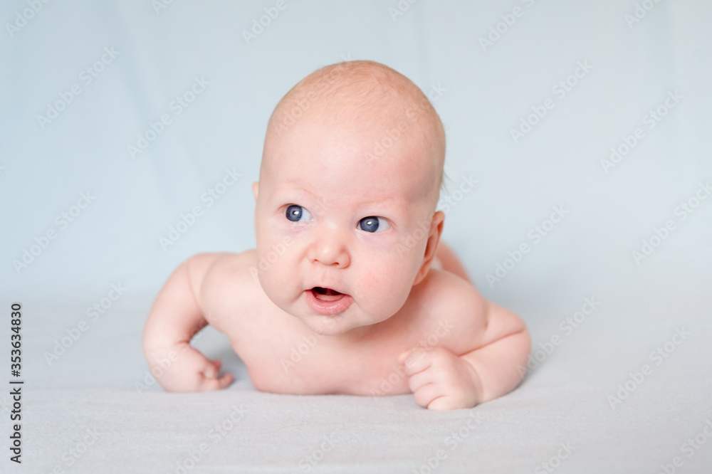 A smiling baby with blue eyes smiles and crawls on a blue sheet. A smiling baby with blue eyes smiles and crawls on a blue sheet.
