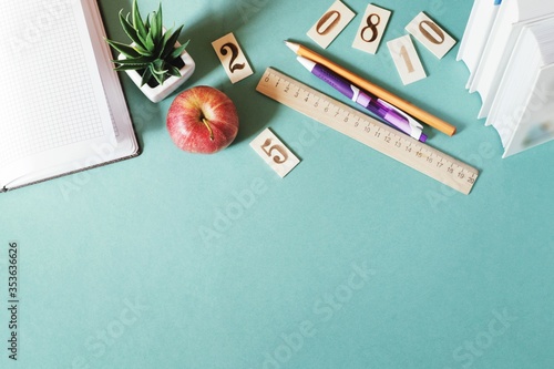 Flat lay photo stationery, books and red apple on a green table. Back to school concept. Mockup, copy space