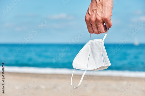 man with a face mask in his hand on the beach