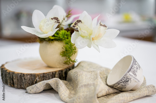 Pot of white flowers on a wooden stand with a cup 