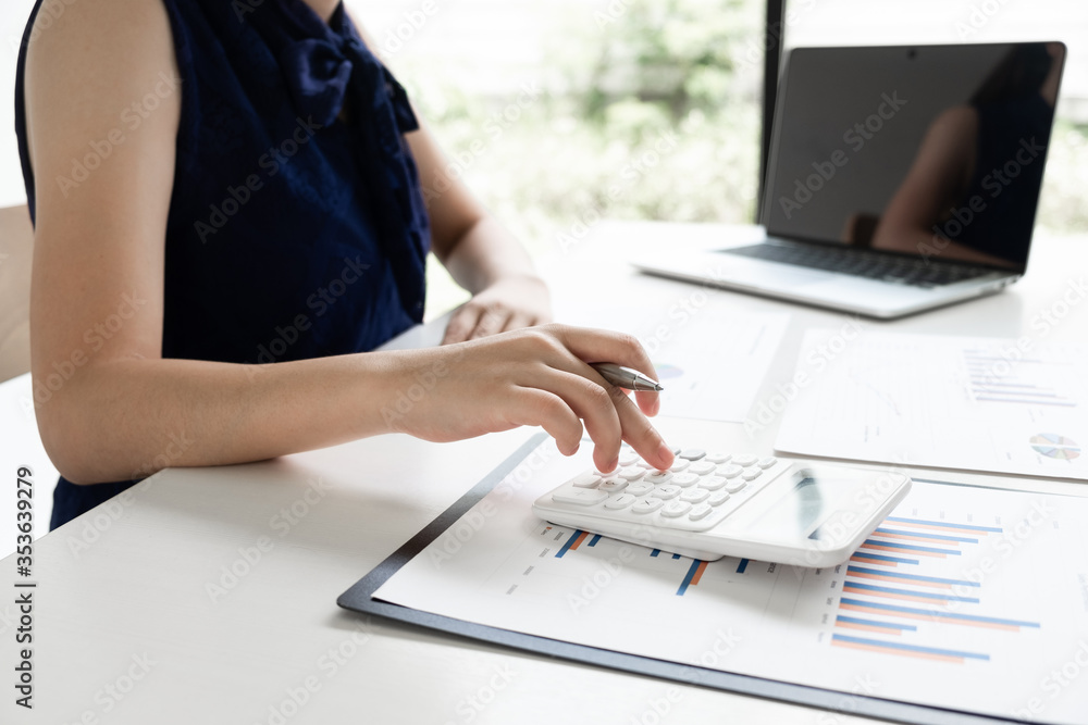 Business women is calculating revenue from graph in the room and work from home. Business women is calculating revenue from graph in the room and work from home.