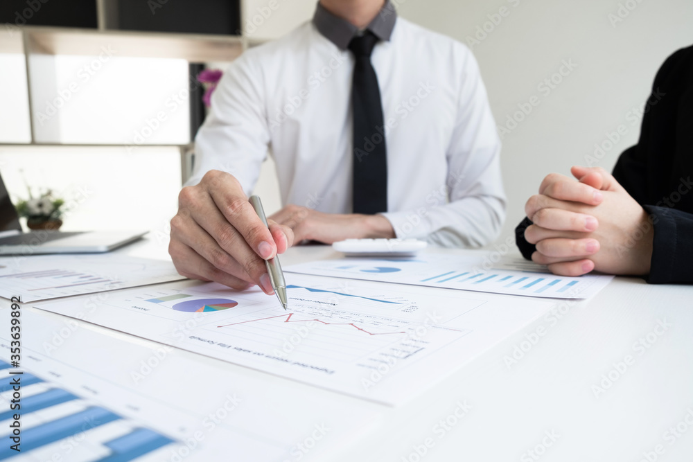Two business people are discussing and analyze marketing strategy from the sell performance graph in the office room. Two business people are discussing and analyze marketing strategy from the sell performance graph in the office room.