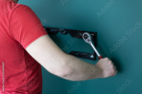 repair and decoration. 'husband for an hour' service. a man attaches a TV mount to a wall.
