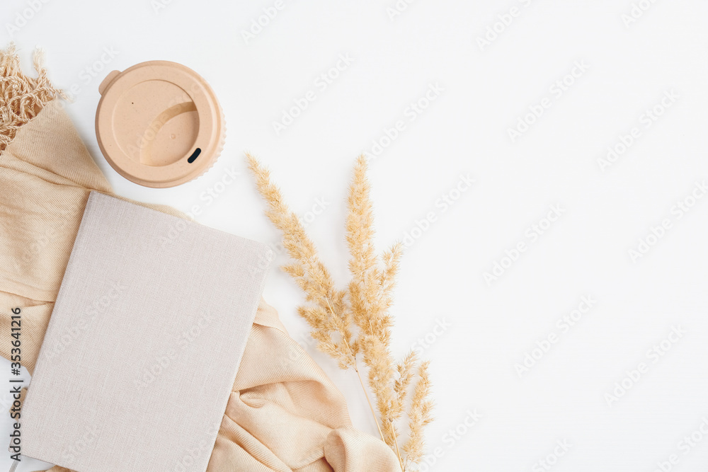 Cozy home office desk with paper notebook, beige blanket, dry flowers and coffee cup on white background. Flat lay, top view. Autumn fall, hygge, nordic style workspace concept. - obrazy, fototapety, plakaty 