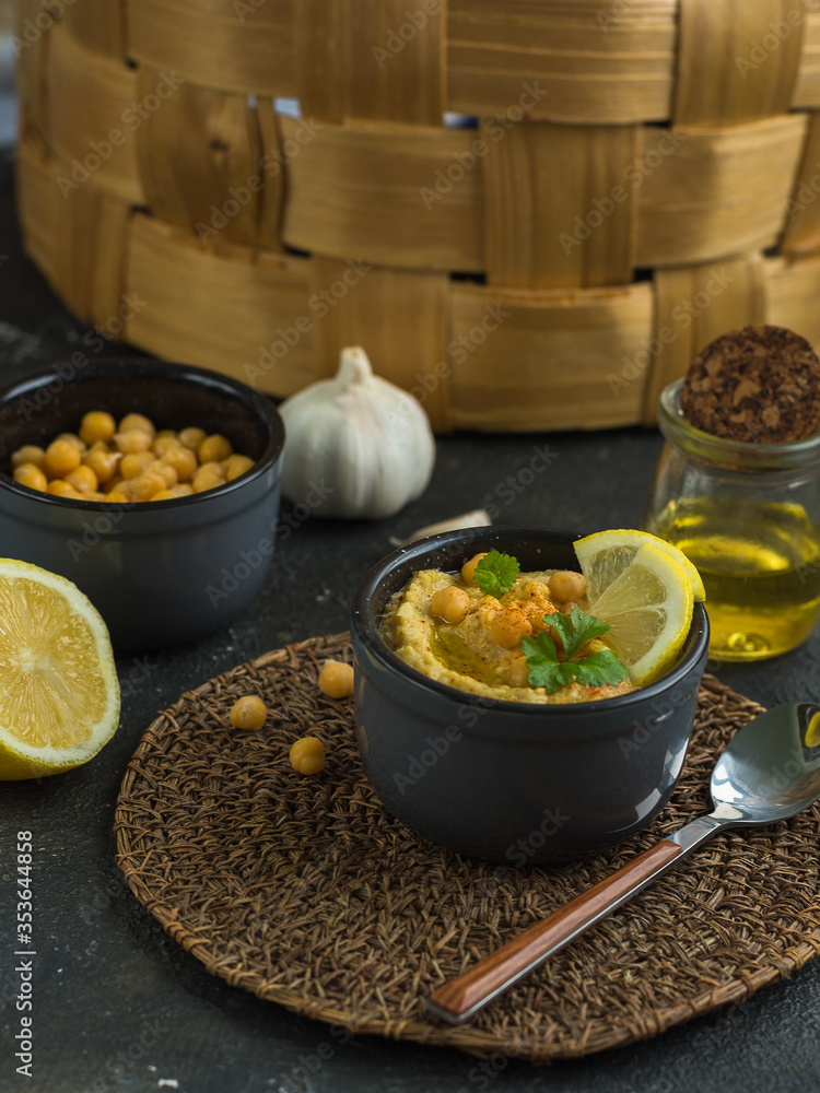 Hummus is a traditional appetizer made from chickpea puree. the products it is made from are chickpeas, lemon, garlic and olive oil, on the background of a wicker basket Hummus is a traditional appetizer made from chickpea puree. the products it is made from are chickpeas, lemon, garlic and olive oil, on the background of a wicker basket
