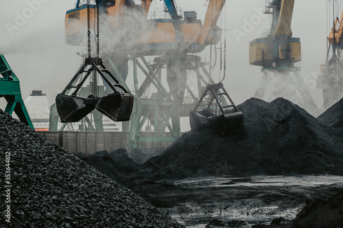 Fototapet port cranes are loading coal into a transporting train.
