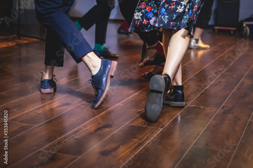 Dancing shoes of young couple dance retro jazz swing dances on a ballroom club wooden floor, close up view of shoes, female and male, dance lessons © tsuguliev