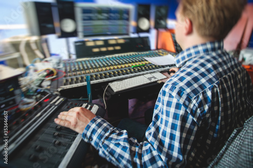 Sound editor engineer working at studio with mixing panel, mixing music and sound, stage sound mixer, boutique recording studio, working during concert performance recording, broadcasting studio © tsuguliev