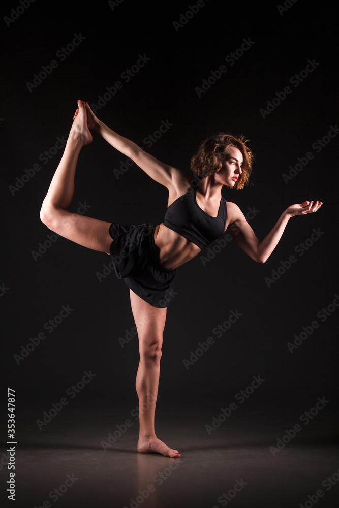 Young girl doing yoga on a black background