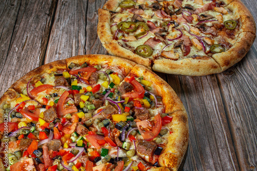 Two different pizzas baked and served on wooden background