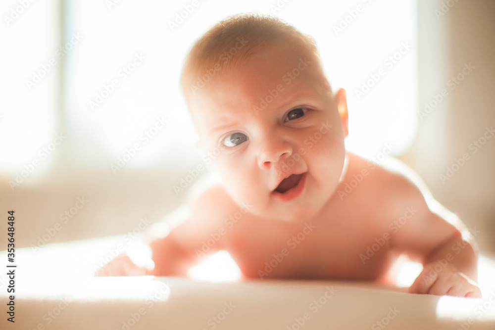 Funny infant laying on the bed in the lights of sun Funny infant laying on the bed in the lights of sun