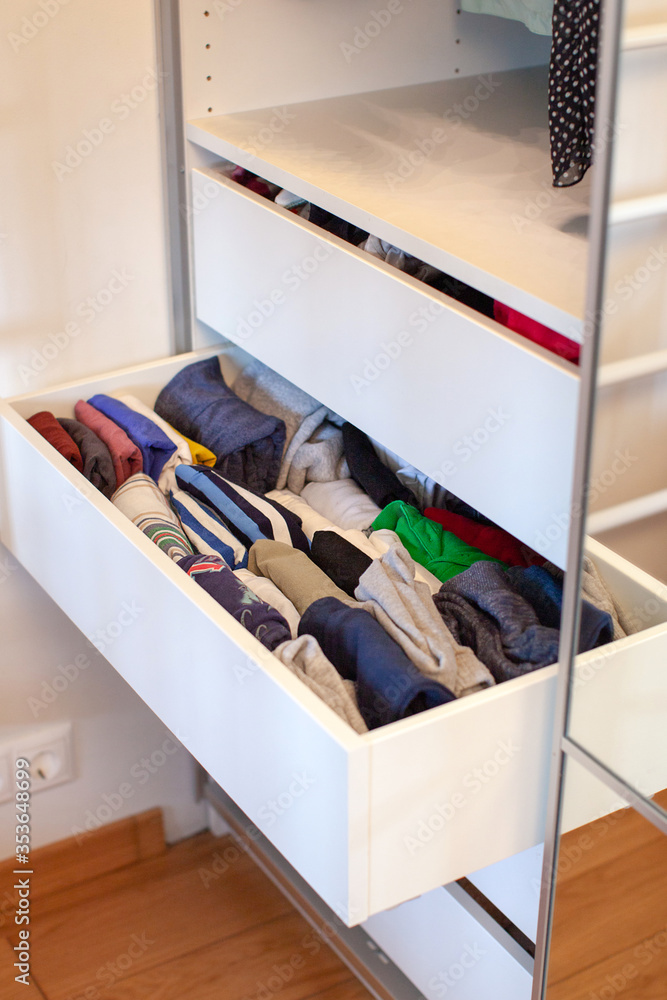Vertical storage of clothing. Clothing folded for vertical storage in the linen drawer. Nursery. Sliding wardrobe. Room interior. Neatly folded clothes in chest of drawers. Newborn baby clothes. Photo...