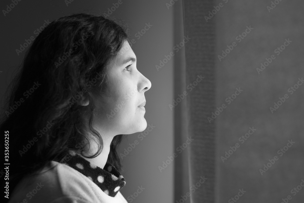 Woman standing in front of the window looking out Woman standing in front of the window looking out