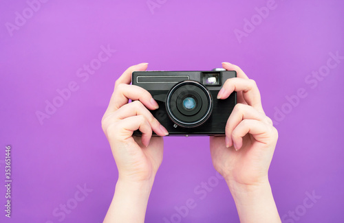 black manual retro camera in hand on a purple background. isolate. banner