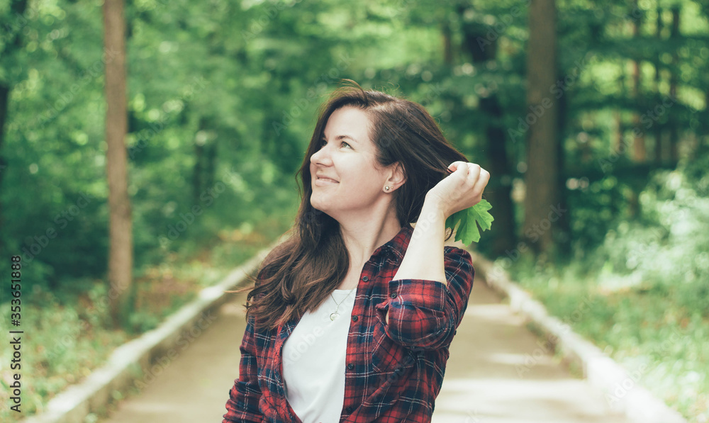
Woman in the forest straightens her hair and smiles