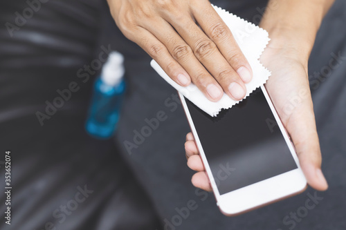 A woman using an alcohol cleaning spray. Mobile phones to prevent the coronavirus