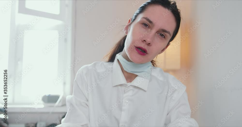 Portrait of serious beautiful brunette Caucasian doctor woman giving advice online looking at camera on self isolation. Portrait of serious beautiful brunette Caucasian doctor woman giving advice online looking at camera on self isolation.