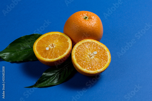a whole orange and two halves of an orange  and two green leaves