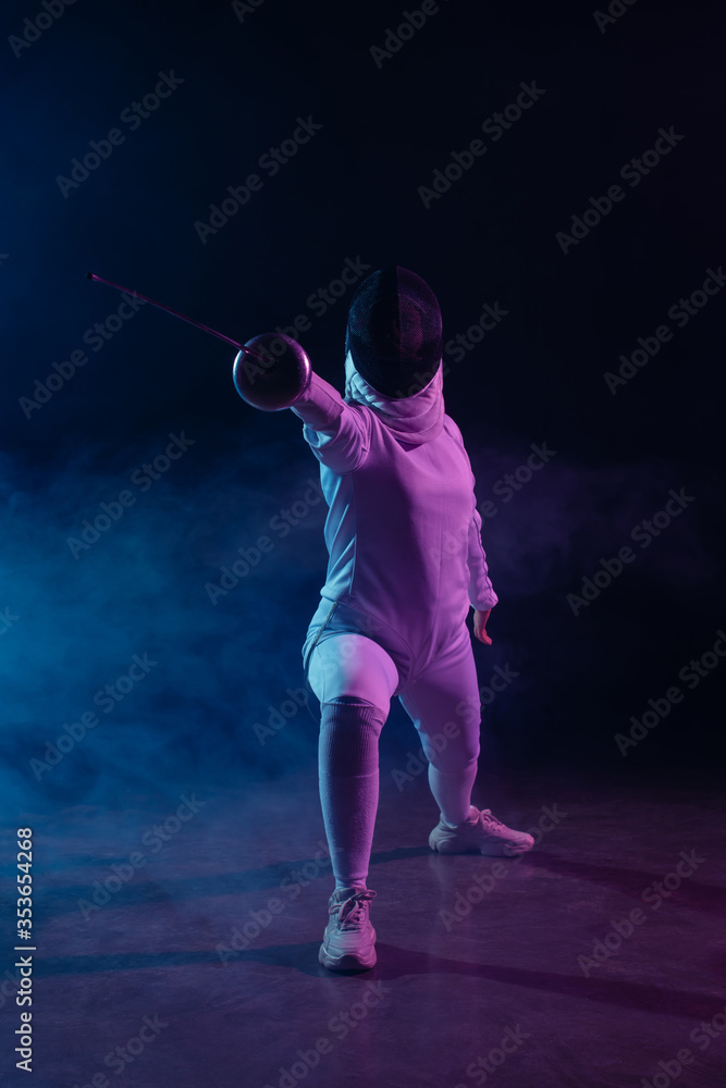 Fencer doing lunge while training with rapier on black background with smoke and lighting Fencer doing lunge while training with rapier on black background with smoke and lighting