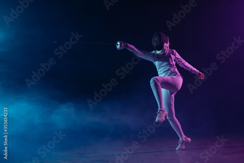 Fencer in fencing mask and suit training with rapier on black background with smoke and lighting © LIGHTFIELD STUDIOS