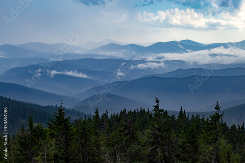 Misty mountain ranges illuminated by the rays of the sun breaking through the cloudy sky